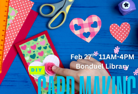 Blue background with paper, scissors, cut out hearts and a card with a finger holding down a rose in front of a handmade card. Text says, "DIY card making."