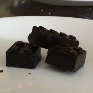 Dark chocolate pieces shaped like Lego bricks on a white surface.