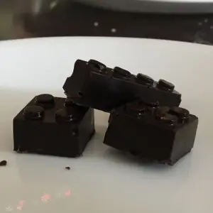 Dark chocolate pieces shaped like Lego bricks on a white surface., links to more information
