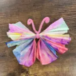 A colorful coffee filter butterfly with pink pipe cleaner antennae, links to more information