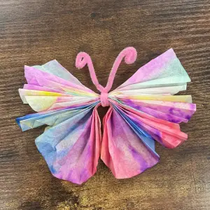 A colorful coffee filter butterfly with pink pipe cleaner antennae, links to more information