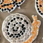 Image of snail made from different colored beans on clay