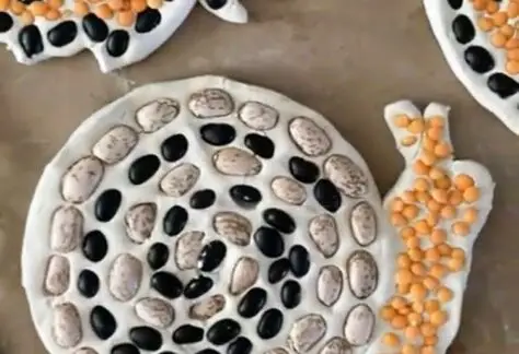 Image of snail made from different colored beans on clay