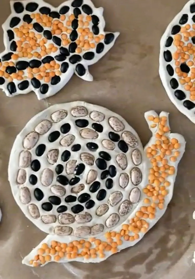 Image of snail made from different colored beans on clay