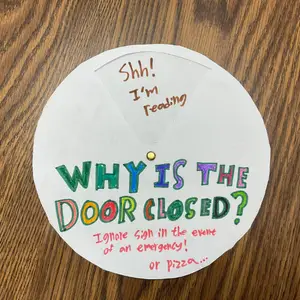 Circular sign with the phrase "WHY IS THE DOOR CLOSED?" in multicolored letters, links to more information