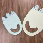 Two blue & green dinosaur footprint paper cutouts on a wooden surface, links to more information