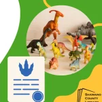 Green background. Plastic dinosaurs standing in many colors. Blue dino print and blue ribbon on a certificate.