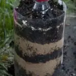 Image shows a plastic bottle layered with dirt and sand.