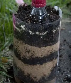 Image shows a plastic bottle layered with dirt and sand.