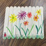 Wooden craft sticks with colorful flower drawings and a ladybug, links to more information