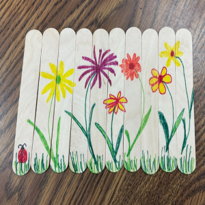 Wooden craft sticks with colorful flower drawings and a ladybug, links to more information