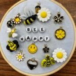 Image of an embroidery hoop with the words "bee happy' and various bee and flower beads