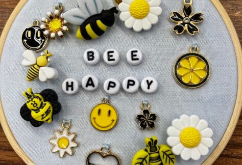 Image of an embroidery hoop with the words "bee happy' and various bee and flower beads