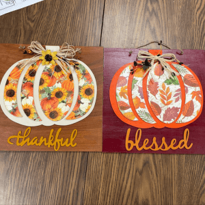 Two floral pumpkins on signs labeled “thankful” and “blessed”, links to more information