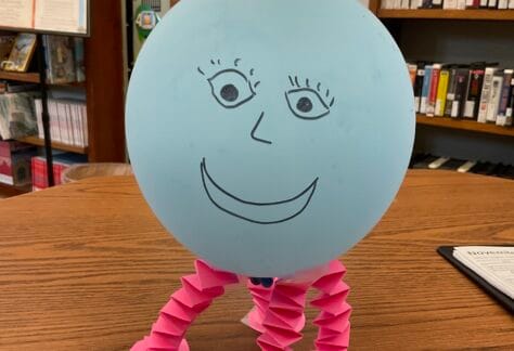Image of a balloon with a face drawn on and paper legs